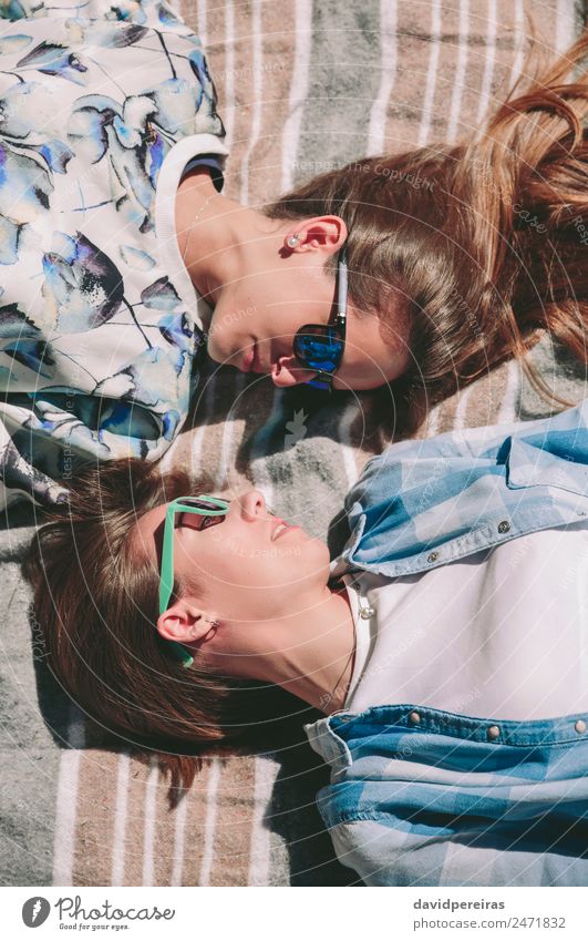 Freundinnen mit Sonnenbrille sehen sich liegend an. Lifestyle Freude Glück schön Erholung Freizeit & Hobby Sommer Sonnenbad Mensch Frau Erwachsene Freundschaft