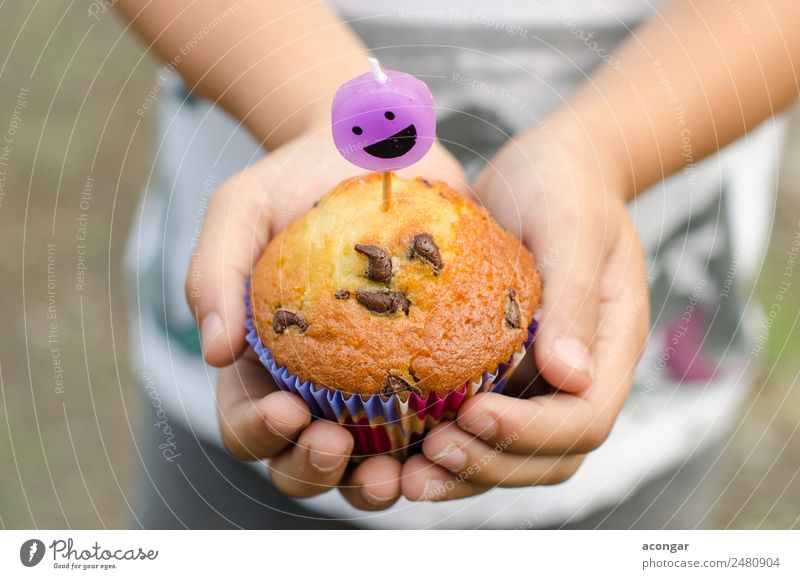 Cupcake und Kerze lächelnd in den Händen eines Kindes. Dessert Glück Tisch Geburtstag Gastronomie Junge Hand Papier Lächeln lecker backen Kuchen Schokolade