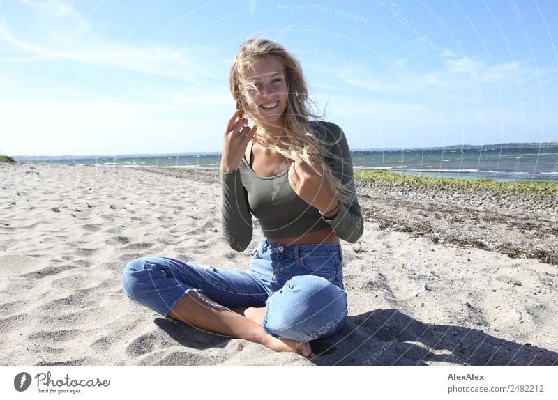 Blonde, junge Frau am Ostseestrand mit wehendem Haar Lifestyle Freude Glück schön Wohlgefühl Sommer Sommerurlaub Sonne Sonnenbad Strand Meer Junge Frau