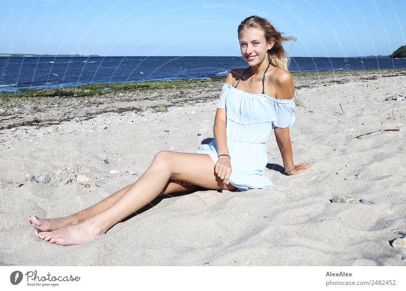 Junge, langbeinige Frau sitzt am Ostseestrand Lifestyle Freude Glück schön Wohlgefühl Erholung Sommer Sommerurlaub Sonne Sonnenbad Strand Meer Junge Frau