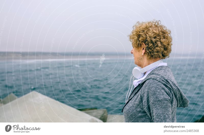 Ältere Sportlerin mit Blick auf das Meer Lifestyle ruhig Freizeit & Hobby Mensch Frau Erwachsene Großmutter Nebel Beton alt sportlich authentisch Gelassenheit