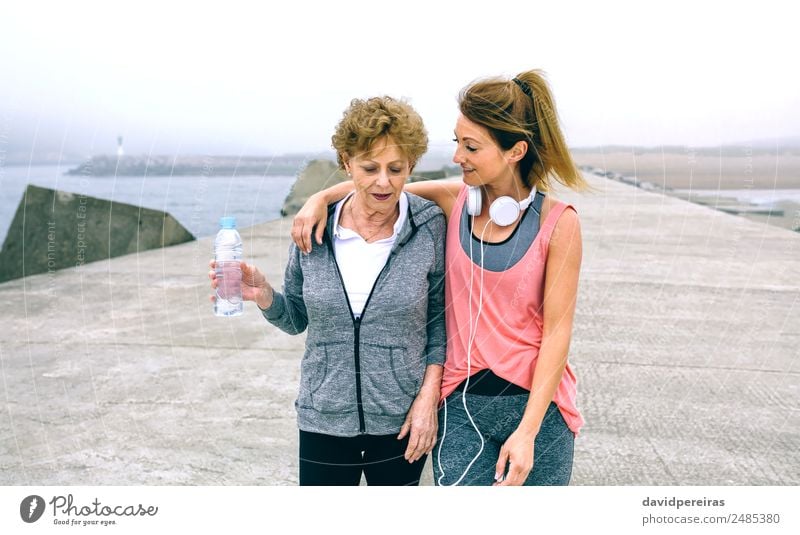 Zwei Frauen, die am Pier spazieren gehen. Flasche Lifestyle Freizeit & Hobby Meer Sport sprechen Mensch Erwachsene Mutter Nebel alt Fitness sportlich