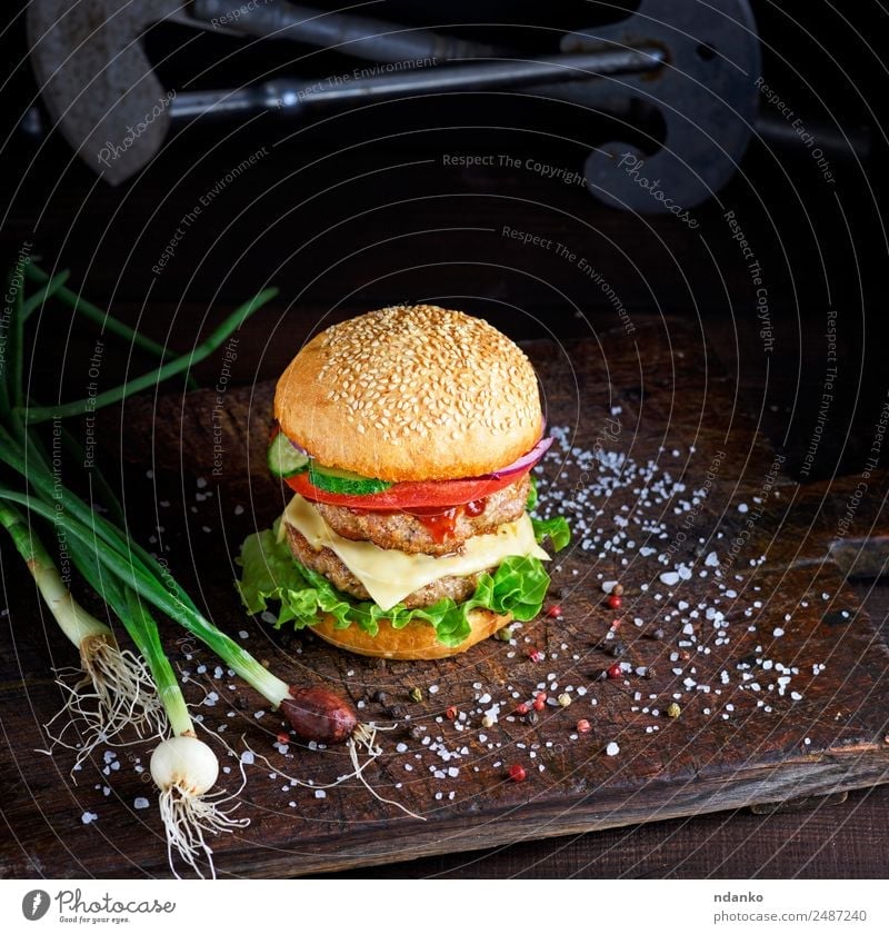 Sandwich mit zwei Fleischschnitzeln Käse Gemüse Brot Brötchen Mittagessen Fastfood Tisch Holz Essen frisch groß lecker grün schwarz Burger Hamburger