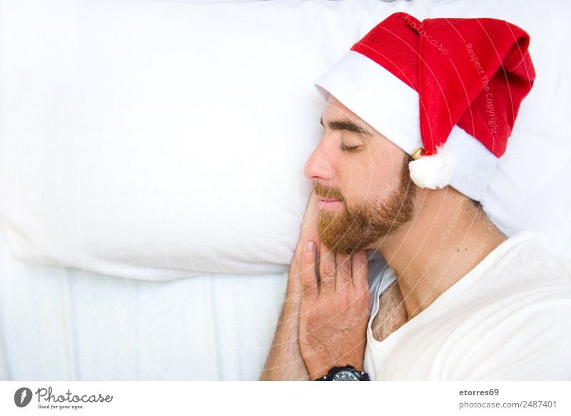 Junger Mann mit Weihnachtsmannmütze schläft im Bett. Kopierbereich links. Party Feste & Feiern Weihnachten & Advent Mensch maskulin Jugendliche Gesicht