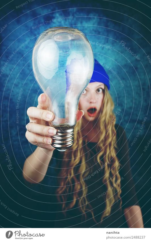 Junge Frau hält eine riesige Glühbirne in der Hand. Lifestyle Stil Design Haare & Frisuren Freizeit & Hobby Technik & Technologie Wissenschaften Fortschritt