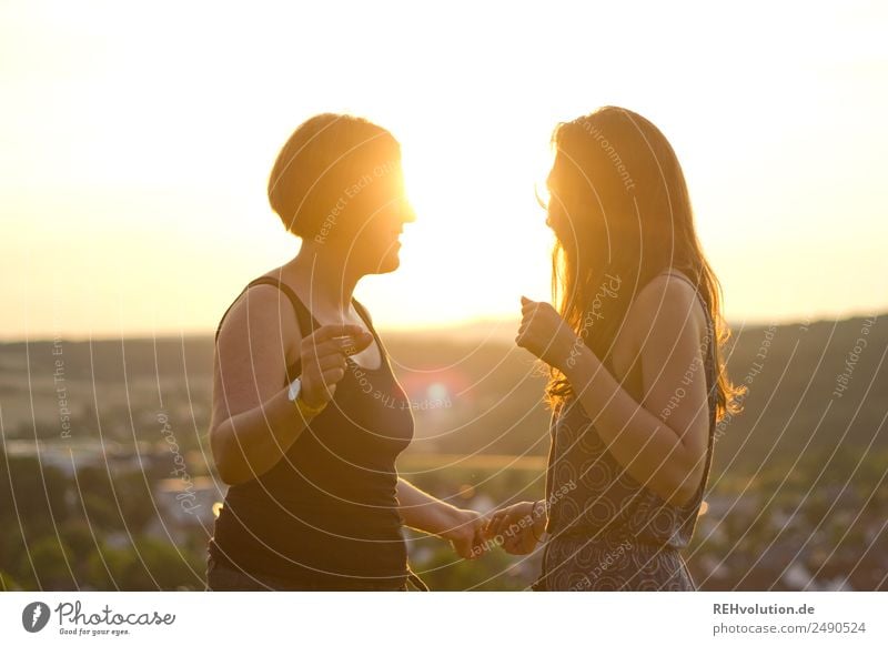 Zwei junge Frauen tanzen in der Sonne Oberkörper Schwache Tiefenschärfe Unschärfe Gegenlicht Sonnenuntergang Sonnenaufgang Sonnenlicht Licht Abend Außenaufnahme