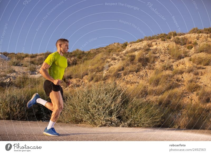 Junger Mann läuft mit grünlich-gelbem Hemd. Lifestyle Sonne Sport Joggen Mensch Erwachsene Park Brücke Bewegung Fitness sportlich Geschwindigkeit weiß rennen