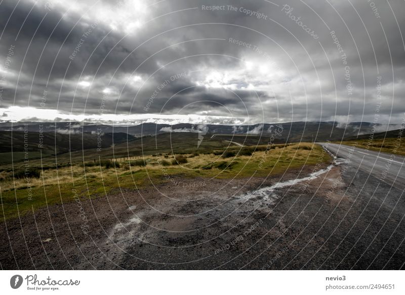 Dunkle Wolken über dem schottischen Hochland Landschaft Wiese Feld bedrohlich dreckig kalt nass trist braun grau dunkel dunkle Wolken Hügel Schotterstraße