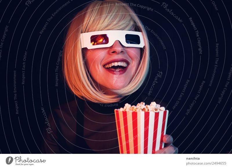 Junge blonde Frau genießt einen Film im Kino Lebensmittel Fastfood Popkorn Lifestyle Stil Freude Freizeit & Hobby Veranstaltung ausgehen Mensch feminin