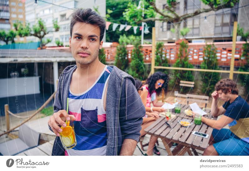 Junger Mann, der im Freien einen mit Wasser angereicherten Cocktail trinkt. Frucht Getränk Saft Lifestyle Freude Glück Freizeit & Hobby Sommer Garten Tisch