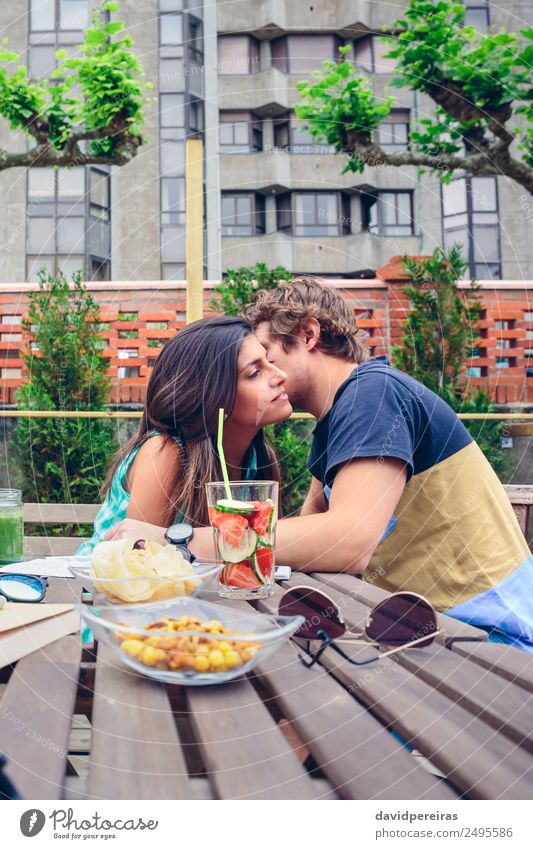 Junger Mann flüstert zu einer Frau, die im Freien sitzt. Gemüse Frucht Getränk Lifestyle Freude Glück Freizeit & Hobby Sommer Garten Tisch Mensch Erwachsene