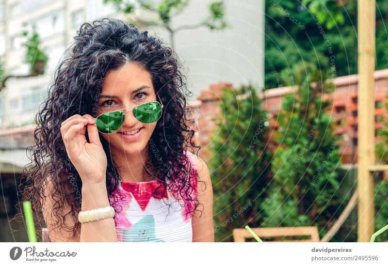 Lächelnde junge Frau schaut auf die Kamera über der Sonnenbrille. Lifestyle Freude Glück schön Gesicht Erholung Freizeit & Hobby Sommer Mensch Erwachsene Baum