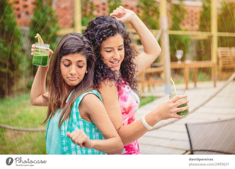 Junge Frauenpaar mit gesunden Getränken, das im Freien tanzt. Gemüse Frucht Alkohol Lifestyle Freude Glück schön Freizeit & Hobby Ferien & Urlaub & Reisen
