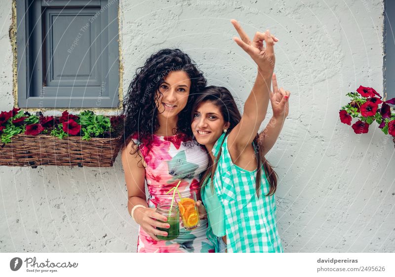 Zwei Frauen mit Getränken, die Siegeszeichen machen. Gemüse Frucht Saft Lifestyle Freude Glück Freizeit & Hobby Sommer Erfolg Mensch Erwachsene Freundschaft