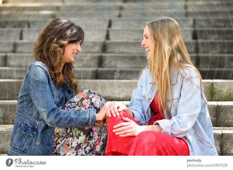 Zwei junge Frauen unterhalten sich lachend auf einer städtischen Treppe. Lifestyle Stil Freude Glück schön sprechen Mensch feminin Junge Frau Jugendliche