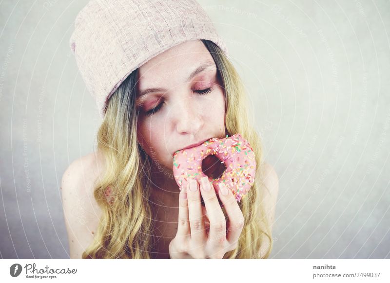 Junge Frau beim Essen eines rosa Donuts Lebensmittel Süßwaren Krapfen Fastfood Lifestyle Stil Design Freude schön Haare & Frisuren Mensch feminin Jugendliche