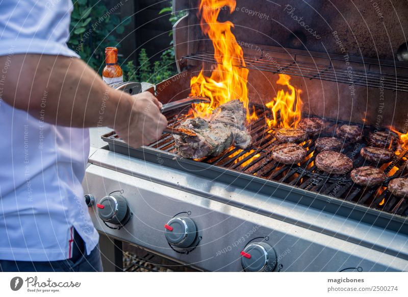 Mann beim Kochen auf dem Grill Fleisch Kräuter & Gewürze Sommer Garten heiß lecker grillen Hinterhof Barbecue Rindfleischburger Beefburger Brand lodernd Burger