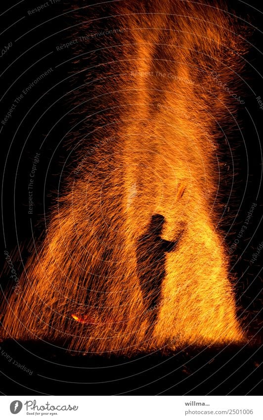 Mensch steht im Funkenregen Feuer Silhouette heiß bedrohlich brennen Brand Flamme gefährlich Brandstiftung Textfreiraum unten Nacht Urelemente