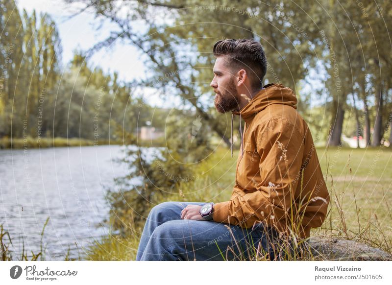 Mann sitzt am Fluss im Herbst. Lifestyle Mensch maskulin Junger Mann Jugendliche Körper 1 18-30 Jahre Erwachsene Natur Landschaft Wasser Baum Feld Flussufer