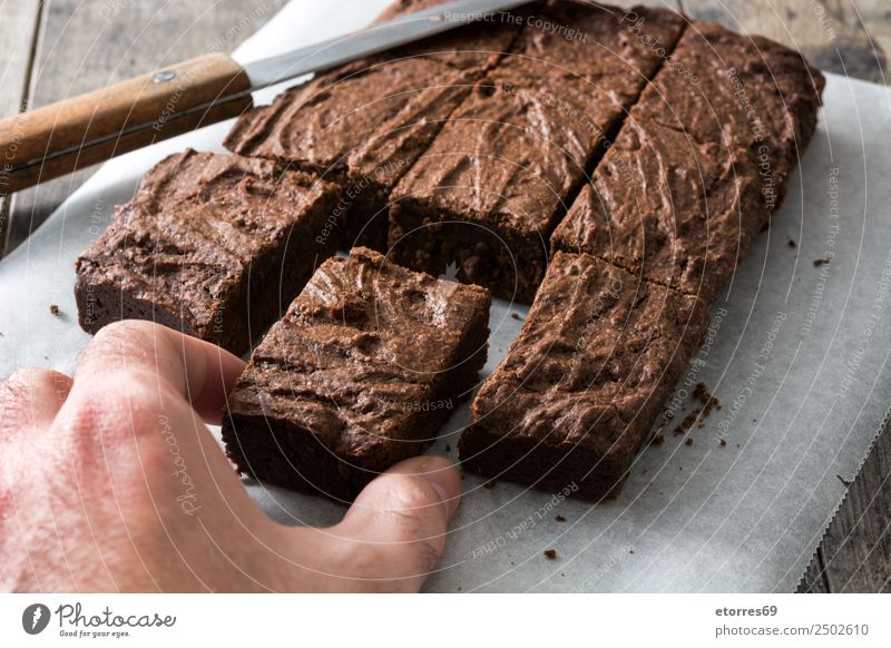 Hand fängt eine Schokoladenbrownie-Portion ein. Lebensmittel Dessert Süßwaren Ernährung Bioprodukte Vegetarische Ernährung Diät Messer Holz schwarz Kuchen