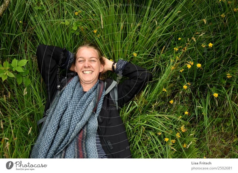 Lachend im Gras liegend. Gesundheit Ferien & Urlaub & Reisen Tourismus Junge Frau Jugendliche 1 Mensch 18-30 Jahre Erwachsene Natur Blume Jacke Schal blond Zopf