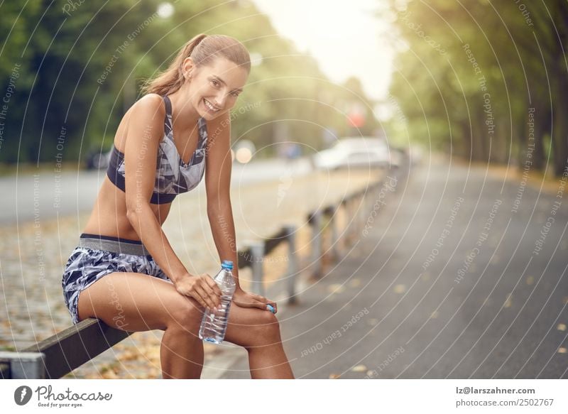 Glückliche Frau, die eine Pause vom Joggen macht. trinken Lifestyle Sommer Sport Erwachsene 1 Mensch 18-30 Jahre Jugendliche Wärme Straße Fitness Lächeln Erfolg