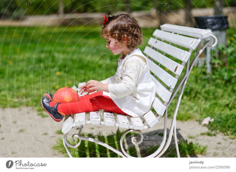Liebenswertes kleines Mädchen spielt mit einem Ball, der auf einer Parkbank sitzt. Lifestyle Freude Glück schön Gesicht Sommer Kind Mensch Kleinkind Frau