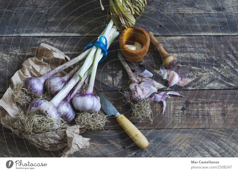 Knoblauchstrauß mit Geschirr auf Holzuntergrund Gemüse Kräuter & Gewürze Ernährung Essen Bioprodukte Messer Küche Natur Pflanze Sommer Nutzpflanze füttern