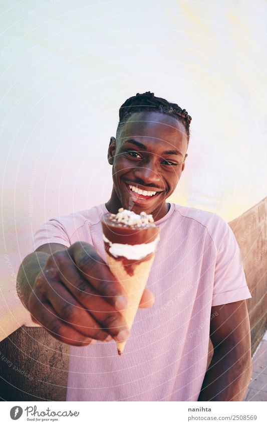 Junger schwarzer Mann hält ein Eis in der Hand. Lebensmittel Speiseeis Ernährung Essen Lifestyle Stil Wellness Sommer Sommerurlaub Mensch maskulin Junger Mann