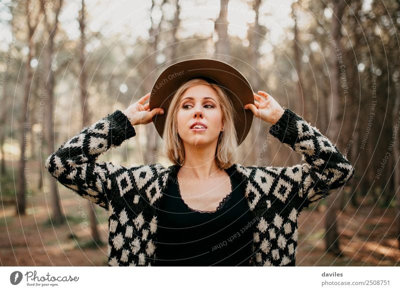 Porträt einer blonden Frau mit den Händen im Hut, die den Wald entdeckt. Lifestyle elegant Stil schön Leben Ferien & Urlaub & Reisen Freiheit Mensch feminin