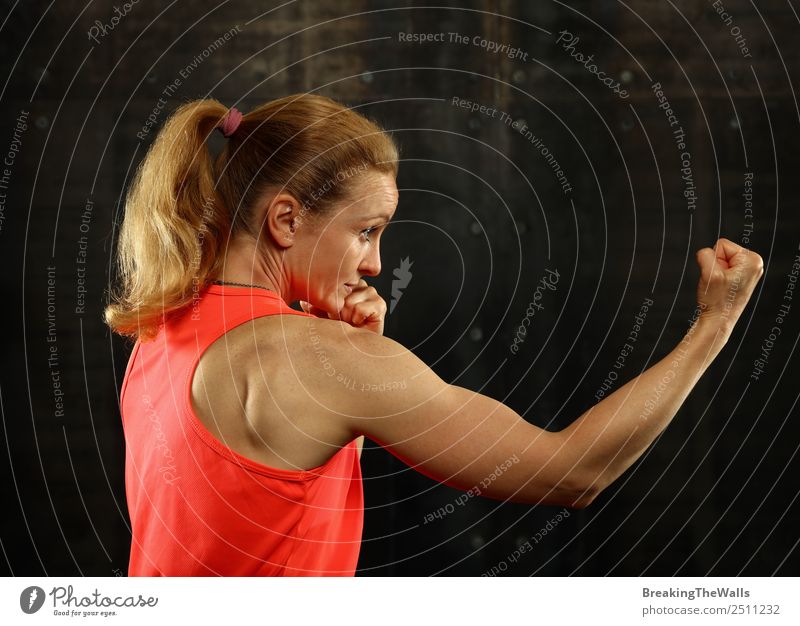 Close up Seitenansicht Profil Porträt eines jungen mittleren Alters sportliche Frau Schattenboxen in Sportkleidung in der Turnhalle über dunklen Hintergrund, Blick weg