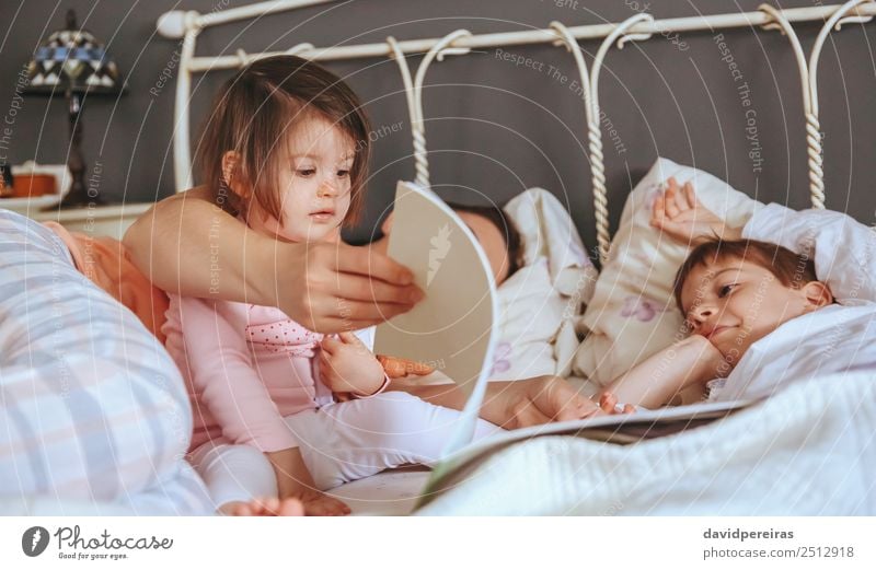 Baby Mädchen beim Lesen Buch mit Familie im Bett Lifestyle Freude Glück schön Erholung Freizeit & Hobby lesen Schlafzimmer Kind Junge Frau Erwachsene Eltern