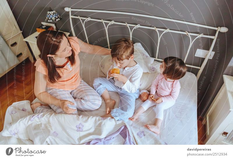 Draufsicht auf glückliche Kinder, die mit ihrer Mutter an einem entspannten Morgen im Bett frühstücken Essen Frühstück Saft Lifestyle Freude Glück schön