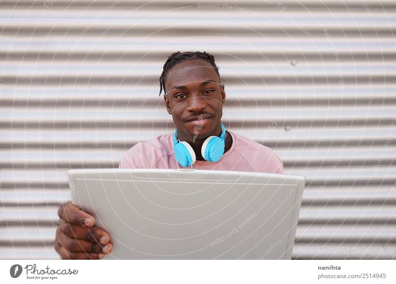 Junger schwarzer Mann mit seinem Laptop Lifestyle Stil Design Schüler Headset Computer Kopfhörer Notebook Technik & Technologie Unterhaltungselektronik Internet