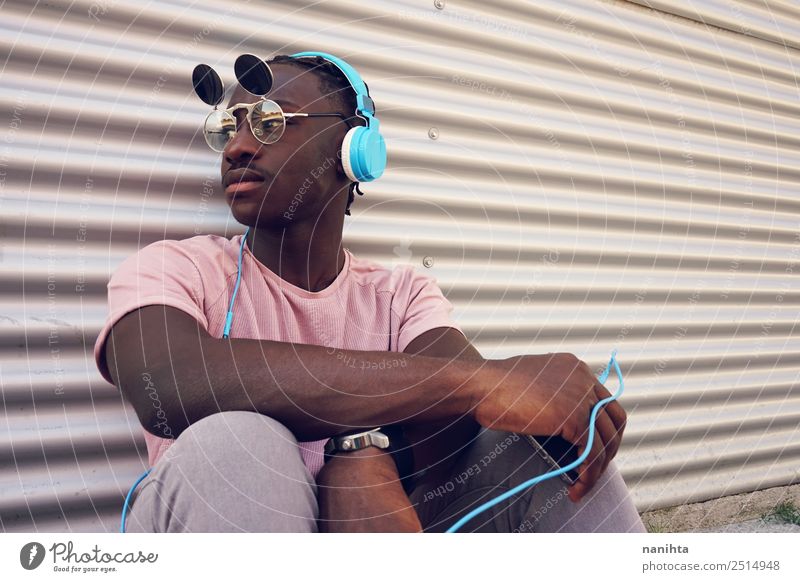 junger schwarzer Mann, der mit seinem Handy Musik hört. Lifestyle Stil Design Freizeit & Hobby Headset Kopfhörer Technik & Technologie Unterhaltungselektronik
