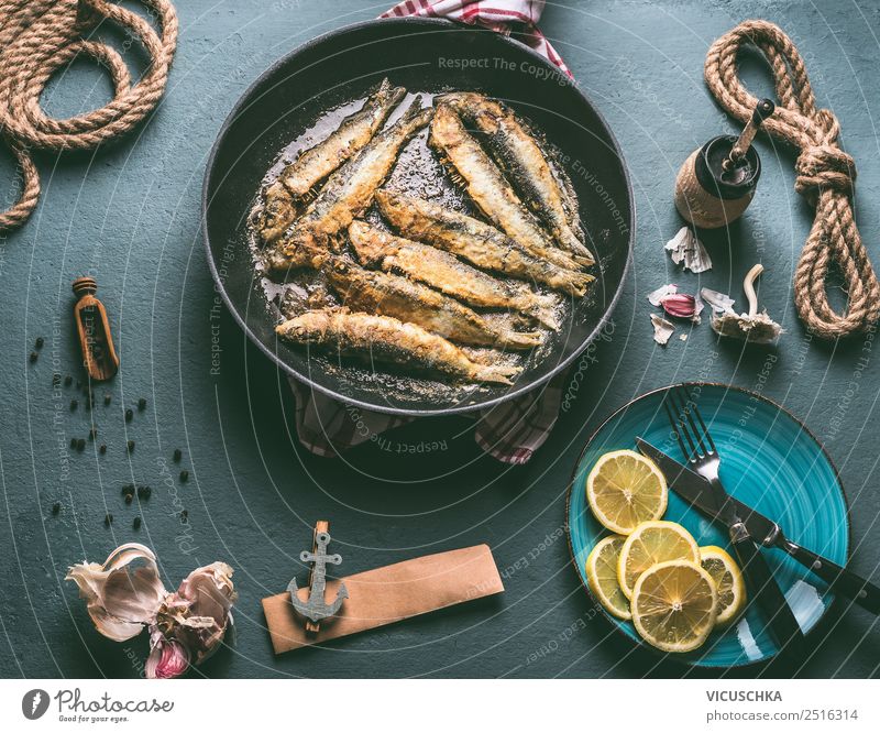 Gebratene Sardinen in der Pfanne auf dem Küchentisch mit Zutaten Lebensmittel Fisch Ernährung Abendessen Bioprodukte Vegetarische Ernährung Geschirr Teller