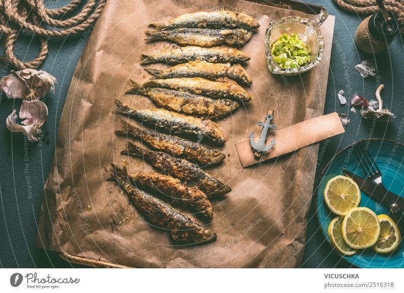 Gegrillte Sardinen auf Backblech mit Zutaten: Zitrone, Knoblauch und Kräuter für schmackhafte Meeresfrüchte. Zubereitung von Fisch zum Kochen gegrillt backen