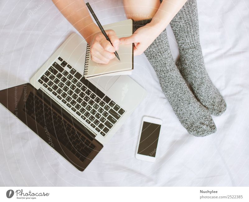 Frauenbeine in Socken und Schreiben auf dem Notebook über Laptop im Bett Lifestyle kaufen Stil Winter Schlafzimmer Arbeit & Erwerbstätigkeit Business Telefon