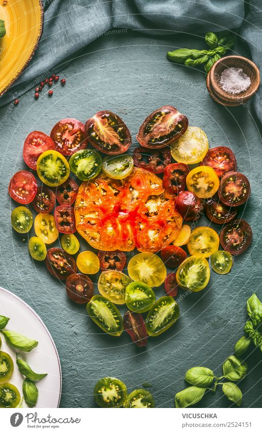 Heart made with colorful halved tomatoes , top view food ingredients kitchenmtable above cooking salad healthy