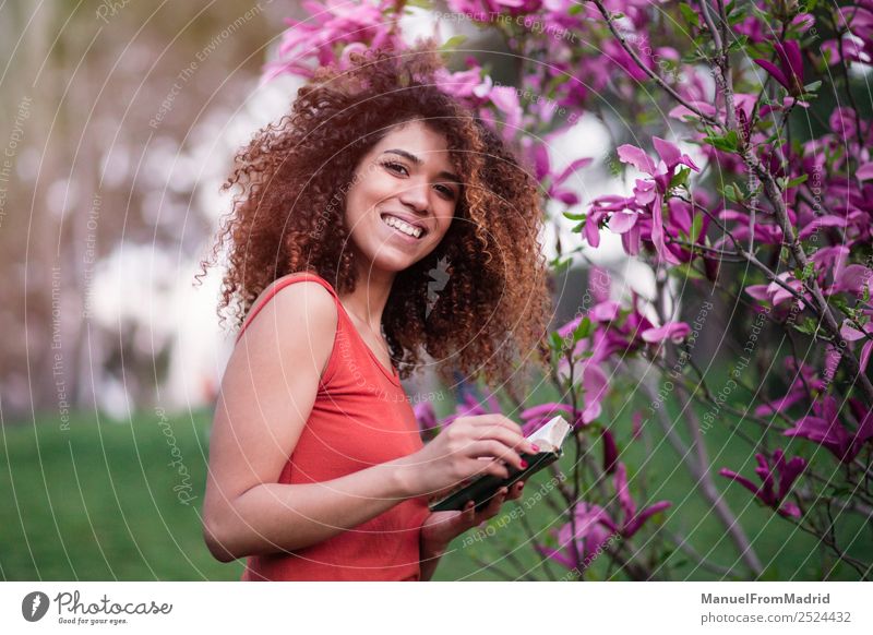 fröhliche Afrofrau, die ein Buch hält. Lifestyle Glück schön Freizeit & Hobby lesen Sommer Garten Schule lernen Fotokamera Mensch Frau Erwachsene Natur Baum