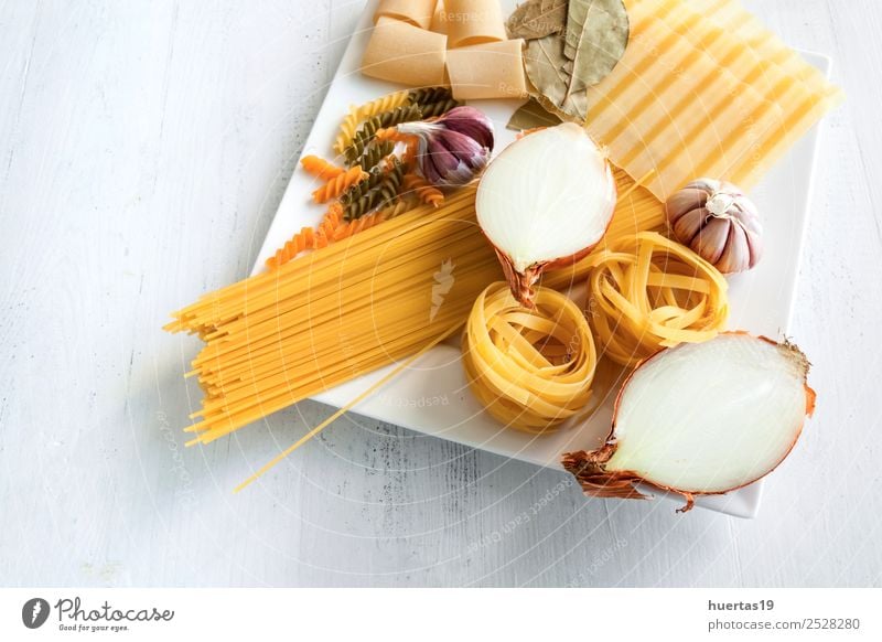 Italienische rohe Nudeln Lebensmittel Italienische Küche Geschirr Teller Gesunde Ernährung gelb grün Spätzle Zwiebeln Knoblauch Olivenöl Spaghetti Fettuccin