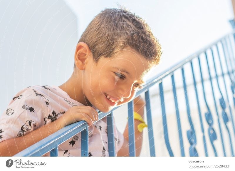 Kleiner Junge, der sich auf ein Geländer in einem weiß-blauen Dorf stützt. Lifestyle Freude Glück schön Gesicht Ferien & Urlaub & Reisen Tourismus Sommer