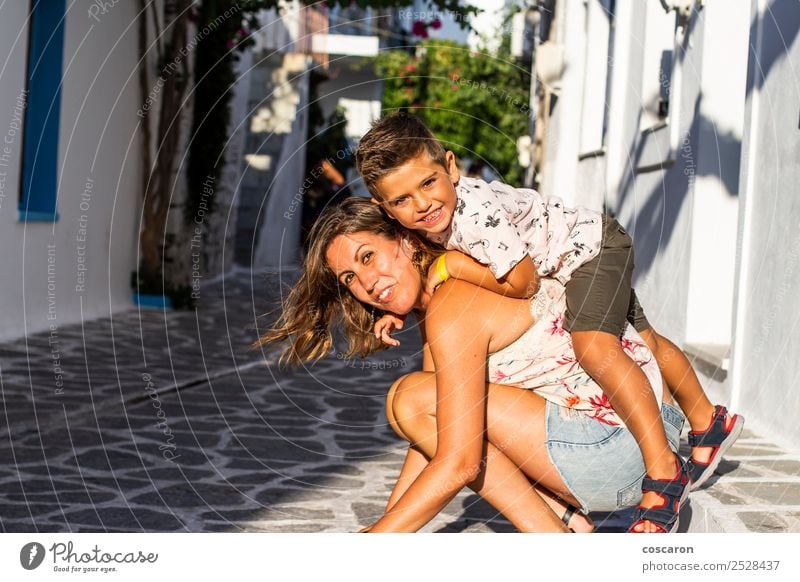 Junge klettert auf dem Rücken seiner Mutter auf der Straße eines griechischen Dorfes Lifestyle Freude Glück schön Spielen Ferien & Urlaub & Reisen Tourismus
