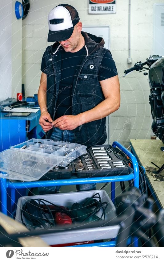 Mechaniker wählt Schrauben aus einem Werkzeugkasten aus. Arbeit & Erwerbstätigkeit Motor Mensch Mann Erwachsene Fahrzeug Motorrad authentisch suchend Muttern