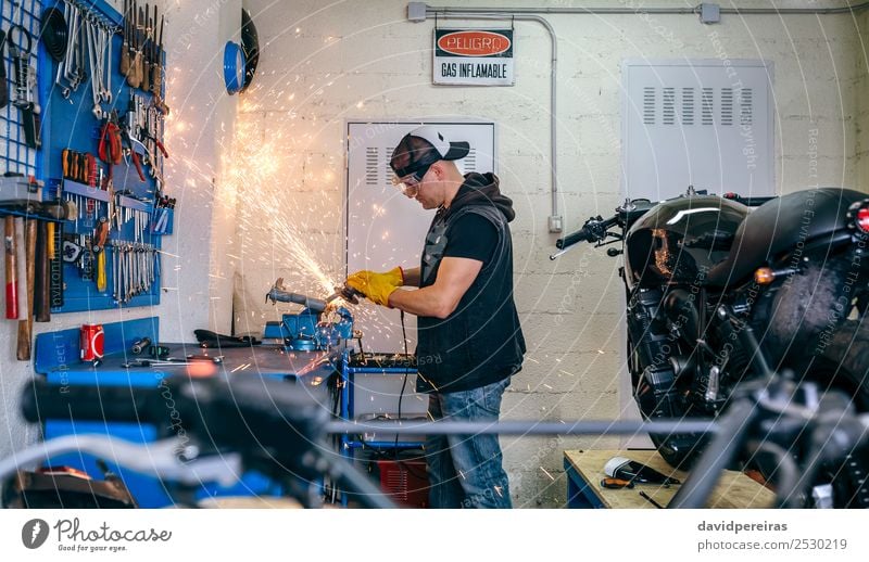 Motorradmechaniker mit einer Schleifmaschine Lifestyle Stil Arbeit & Erwerbstätigkeit Mensch Mann Erwachsene Fahrzeug Jeanshose Handschuhe authentisch retro