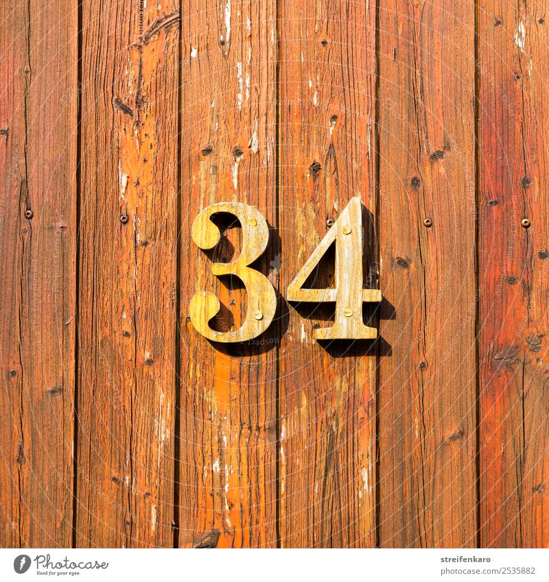 Holzziffern 34 auf einer der Tür aus Holzlatten Wohnung Haus Hausnummer Gebäude Ziffern & Zahlen Zeichen ästhetisch braun gelb Design Handwerk Farbfoto