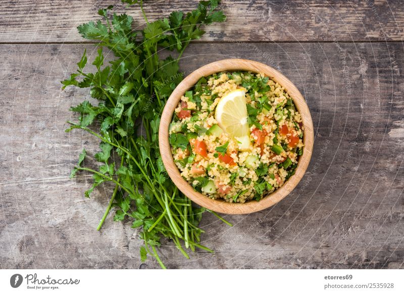 Tabbouleh-Salat mit Couscous auf einem Holz. Tisch Salatbeilage Gemüse Tomate Gurke Salatgurke Petersilie Minze Vegane Ernährung Vegetarische Ernährung