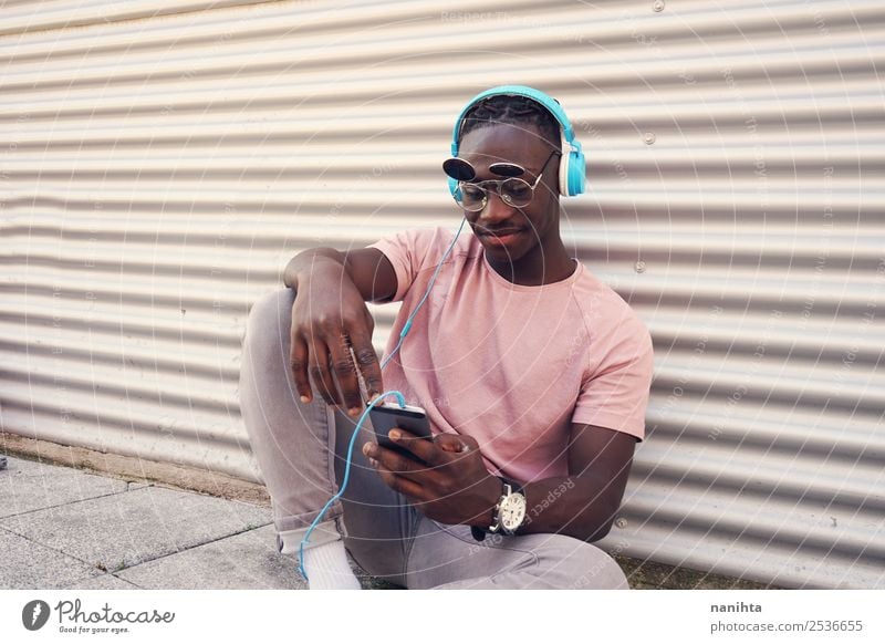 Junger Mann hört Musik und benutzt sein Smartphone. Lifestyle Stil Design Freude Freizeit & Hobby Freiheit Handy Headset PDA Kopfhörer Technik & Technologie