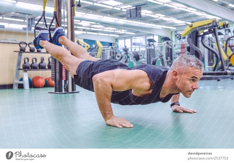 Hübscher Mann beim harten Suspensionstraining mit Fitnessbändern in einem Fitnesscenter Lifestyle schön Körper Club Disco Sport Seil Mensch Erwachsene