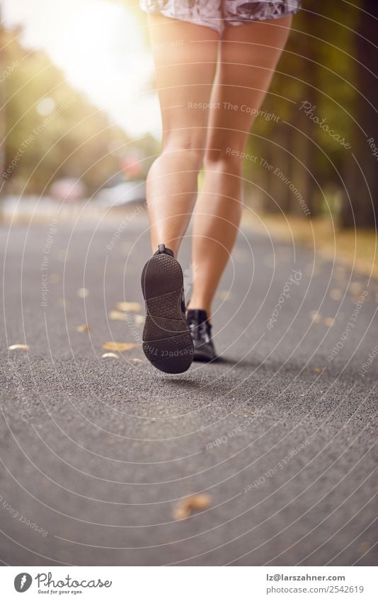 Junge Frau beim Joggen auf einer Herbststraße Lifestyle Erholung Sommer Sonne Sport Mensch Erwachsene Fuß 1 18-30 Jahre Jugendliche Straße Schuhe Fitness hinten